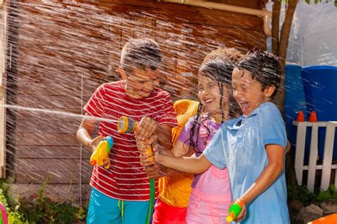 Kinderen die spelen met waterpistolen en bellenblaasmachines in een tuin