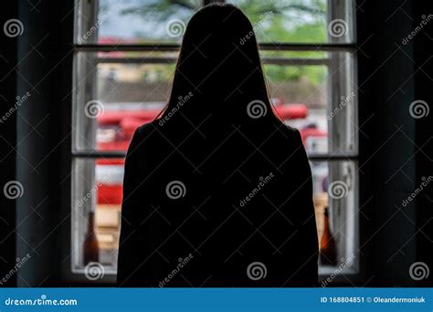 Vrouw in silhouet tegen een raam met een zwangerschapsbuik