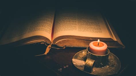 een afbeelding van een Bijbel met een kaars ernaast