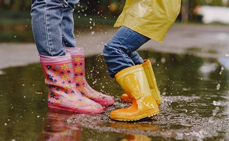Kinderen in regenlaarzen die vrolijk in plassen stampen.
