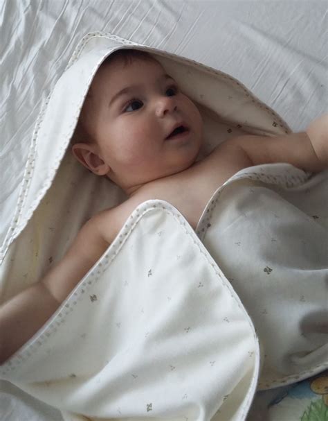 Een baby met een zachte, geborduurde badcape om zich heen gewikkeld