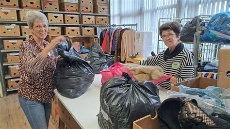 Vrijwilligers die tweedehands kleding sorteren in een winkel van Terre des Hommes