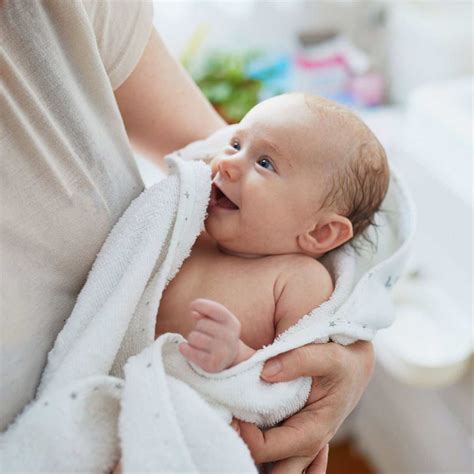 Een ouder die met een grote badhanddoek met capuchon een baby uit bad tilt, de grond blijft droog.