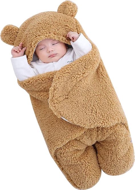 Pasgeboren baby ingewikkeld in een zachte wrap, liggend op een deken in de studio