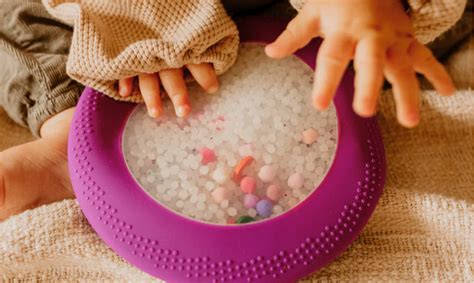 Kinderen die met hun handen verschillende texturen voelen in bakken