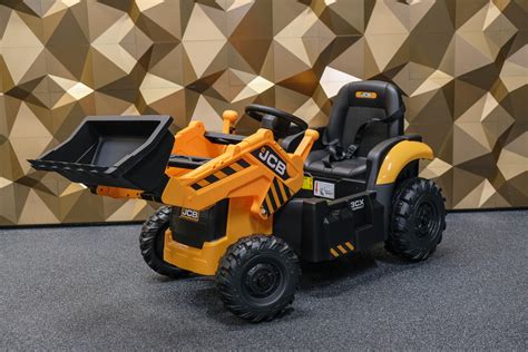 Een kind met een JCB kindertractor met aanhanger, spelend in de tuin.