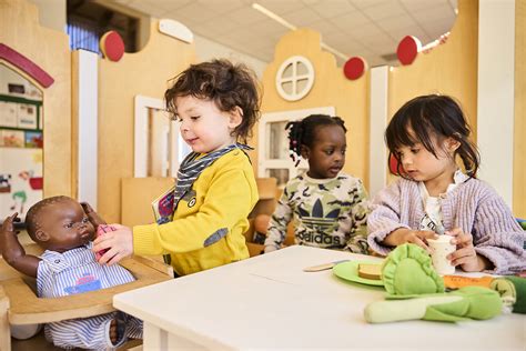 Peuter die met poppen speelt in een nagebouwd huisje, illustreert fantasie en rollenspel.