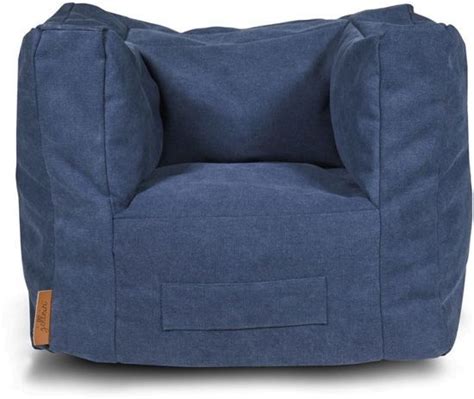 Een kind zit comfortabel in het Jollein fauteuiltje stonewashed canvas navy in een lichte woonkamer.