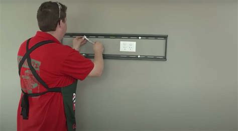 Stapsgewijze illustratie van het monteren van een babyfooncamera aan de muur met een beugel.